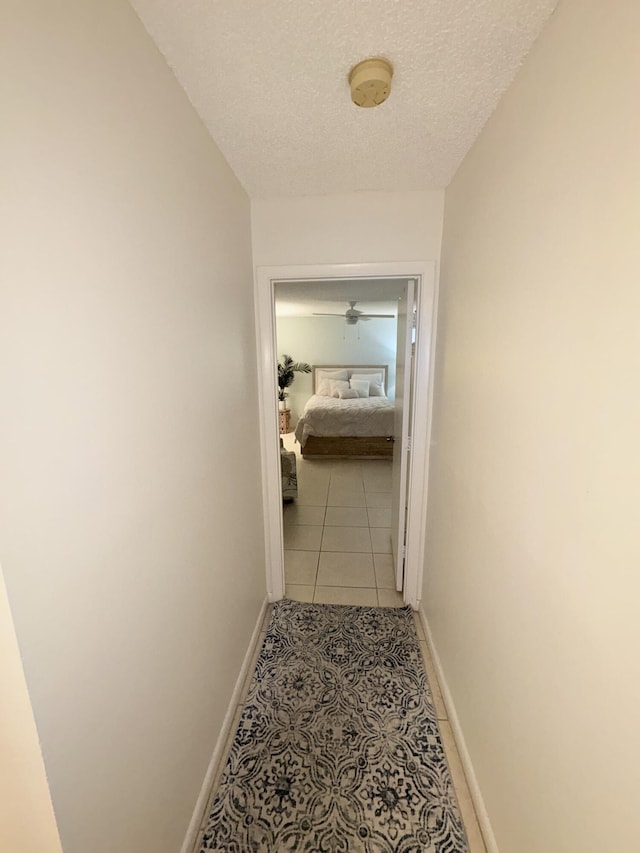 corridor with light tile patterned floors and a textured ceiling