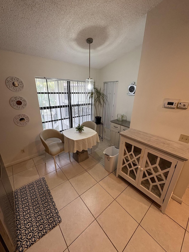 tiled dining space featuring a textured ceiling and lofted ceiling