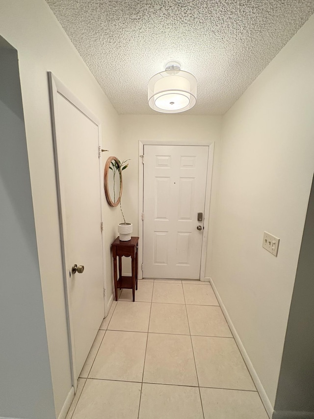 hall featuring light tile patterned flooring and a textured ceiling