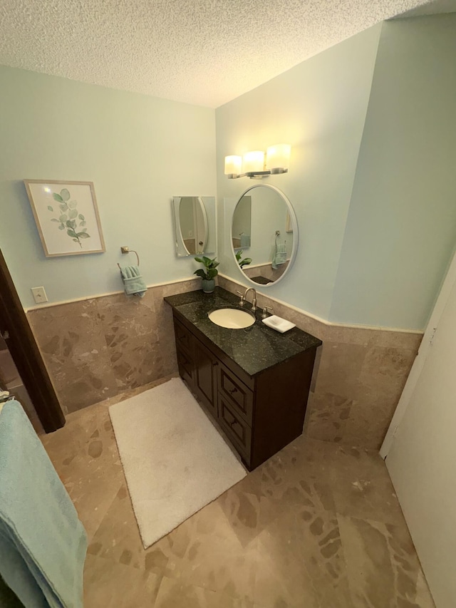 bathroom with vanity, tile walls, and a textured ceiling