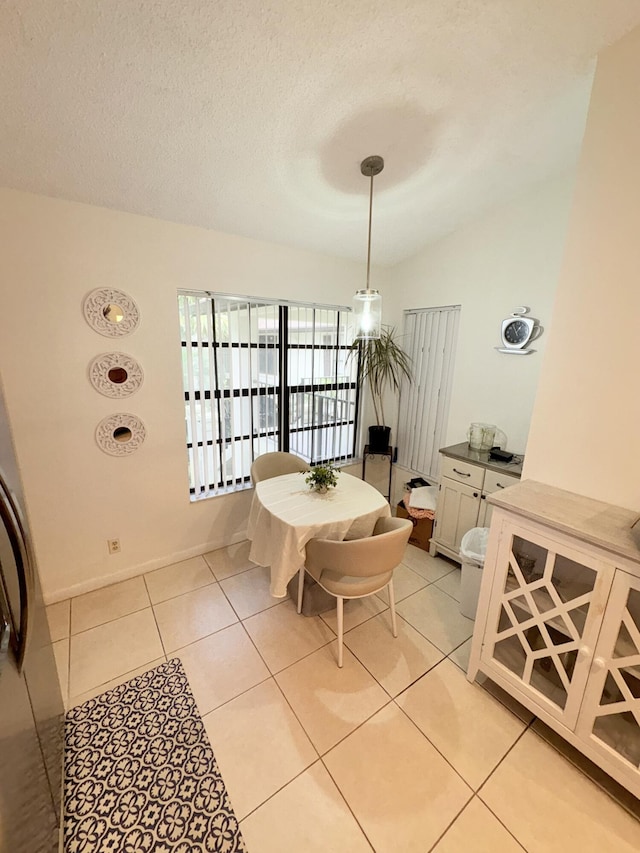 tiled dining room featuring a textured ceiling and vaulted ceiling