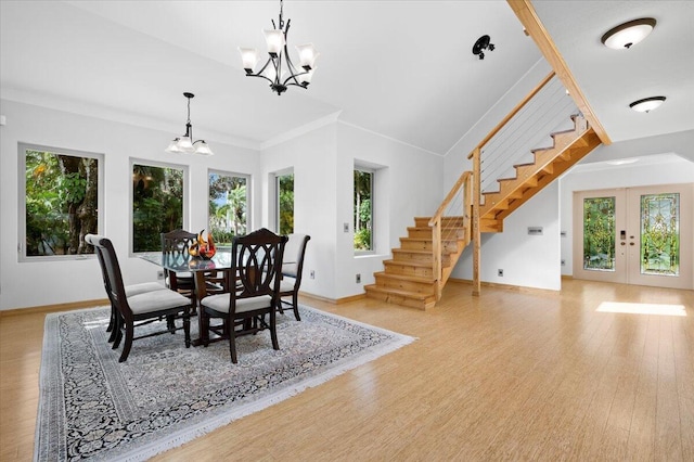 dining space with a notable chandelier, plenty of natural light, light hardwood / wood-style floors, and french doors