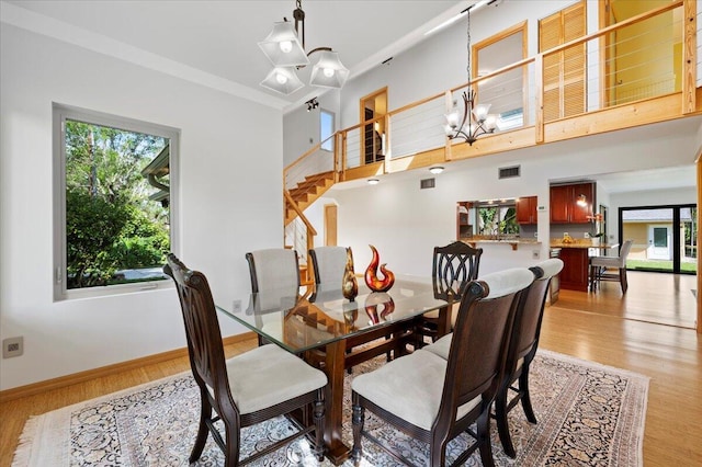 dining space with a towering ceiling, an inviting chandelier, and light hardwood / wood-style flooring