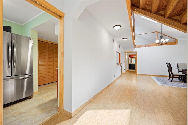 corridor featuring crown molding, light wood-type flooring, and an inviting chandelier