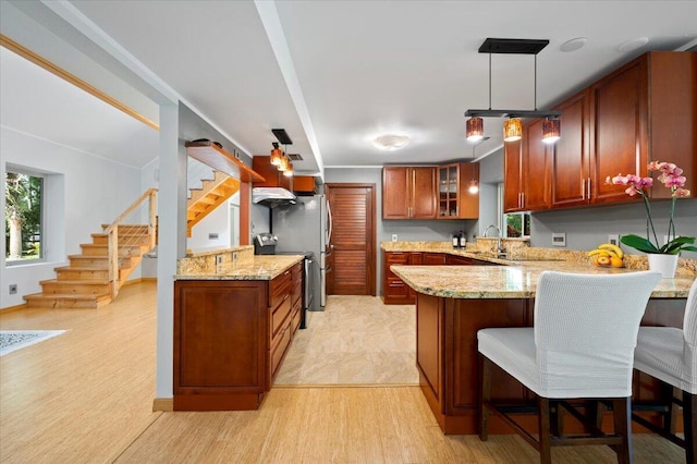 kitchen featuring light stone counters, sink, decorative light fixtures, and kitchen peninsula