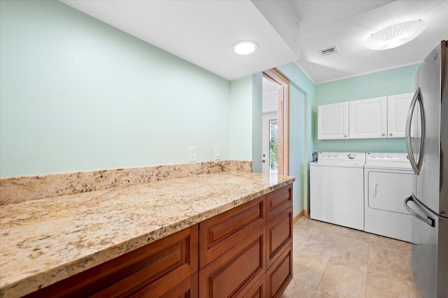 clothes washing area with washing machine and dryer and cabinets