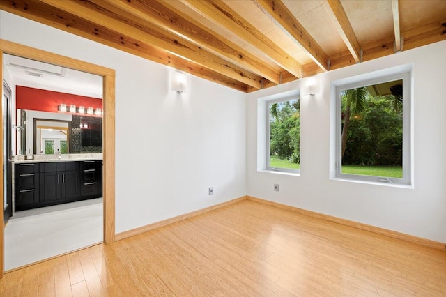 empty room with hardwood / wood-style flooring and beamed ceiling