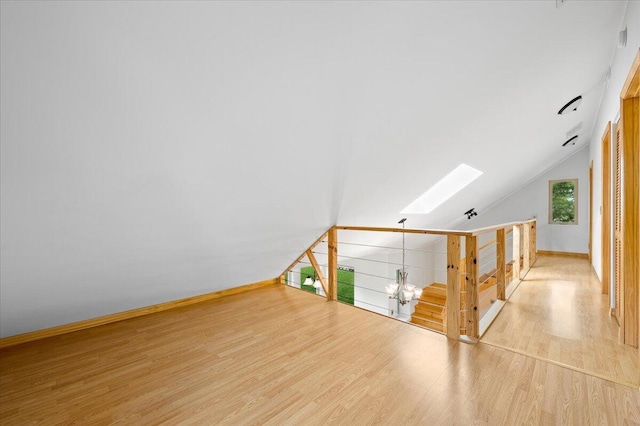 additional living space featuring vaulted ceiling with skylight and hardwood / wood-style floors