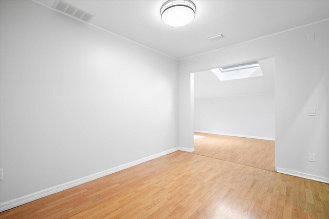 unfurnished room featuring a skylight and light wood-type flooring