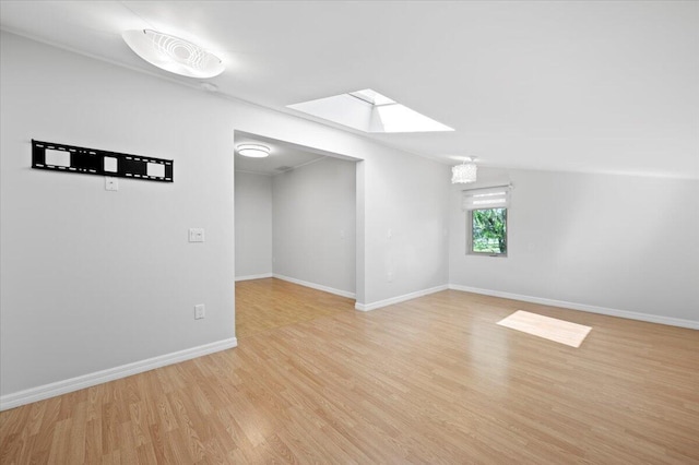 empty room featuring light hardwood / wood-style flooring and vaulted ceiling with skylight