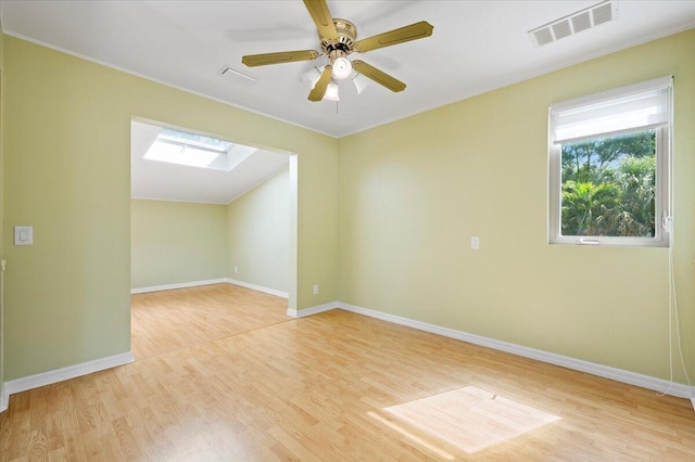 empty room with ceiling fan, a skylight, and light hardwood / wood-style flooring