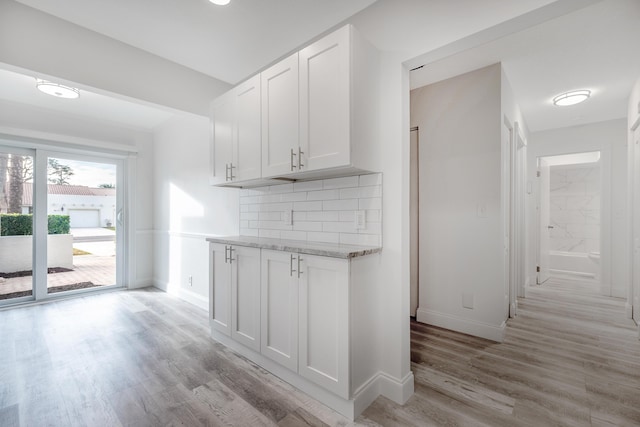 kitchen with light hardwood / wood-style floors, white cabinets, and tasteful backsplash