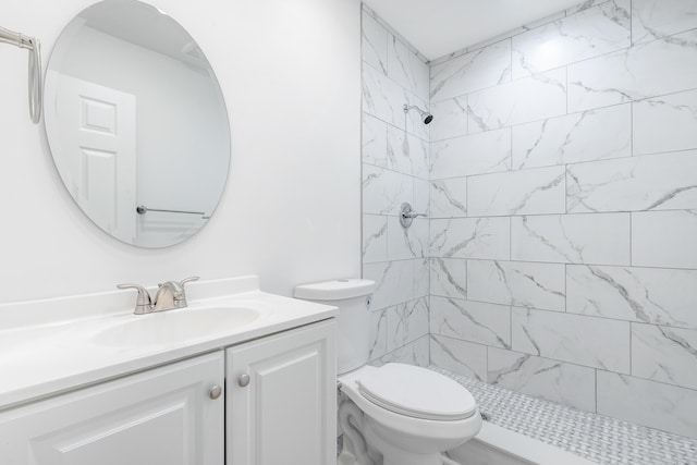 bathroom featuring toilet, vanity, and a tile shower