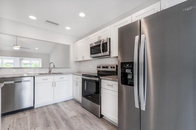 kitchen featuring light stone countertops, white cabinets, stainless steel appliances, ceiling fan, and light hardwood / wood-style flooring