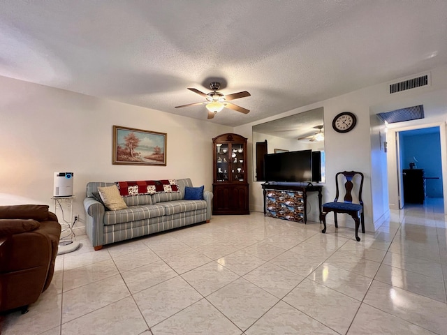 living room featuring ceiling fan and a textured ceiling