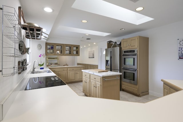 kitchen featuring a kitchen island, sink, a skylight, appliances with stainless steel finishes, and light tile patterned floors