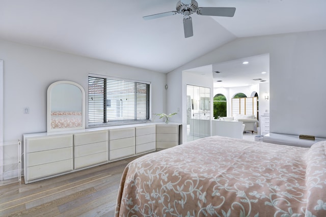 bedroom featuring ceiling fan, connected bathroom, lofted ceiling, and light wood-type flooring