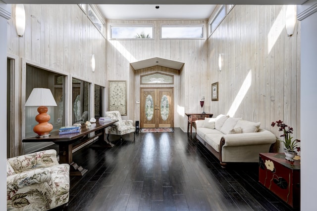 foyer entrance featuring a high ceiling, dark hardwood / wood-style flooring, french doors, and wooden walls