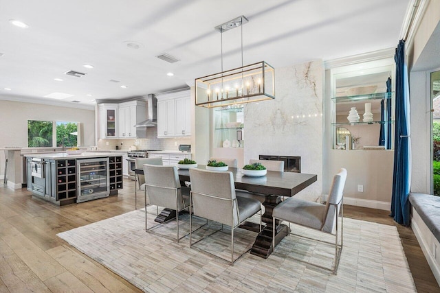 dining room with crown molding, wine cooler, and light wood-type flooring