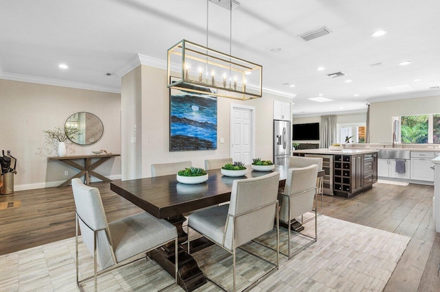 dining area with ornamental molding and light hardwood / wood-style flooring