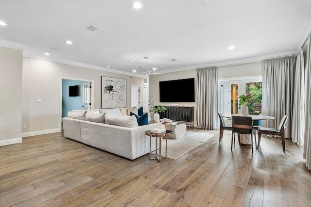 living room with ornamental molding, a chandelier, and light hardwood / wood-style floors