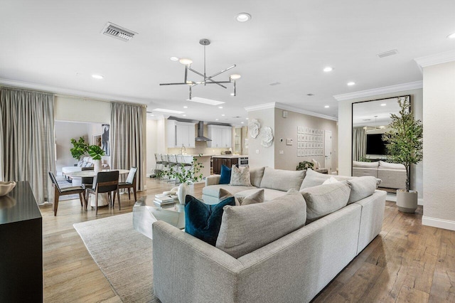 living room with ornamental molding, a notable chandelier, and light hardwood / wood-style floors