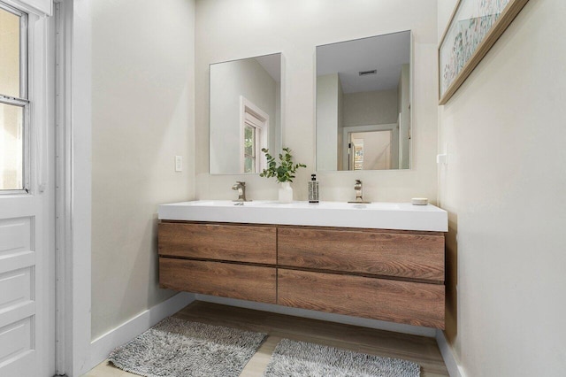 bathroom with vanity, hardwood / wood-style flooring, and a healthy amount of sunlight