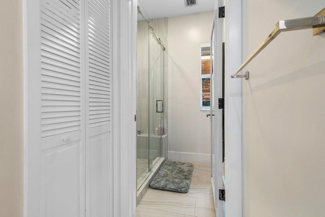 bathroom with an enclosed shower and tile patterned flooring