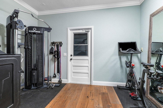 workout area with crown molding and hardwood / wood-style floors