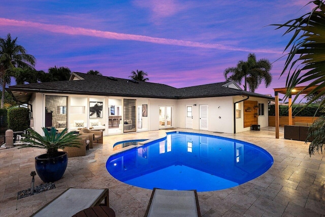 pool at dusk featuring an in ground hot tub, outdoor lounge area, and a patio area