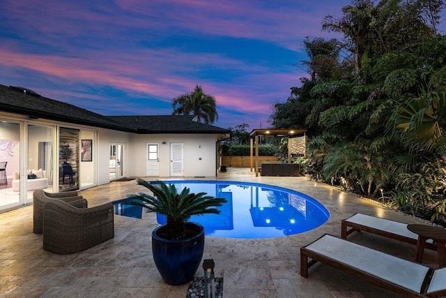 pool at dusk featuring outdoor lounge area and a patio area