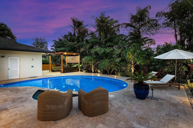 pool at dusk with a pergola and a patio area