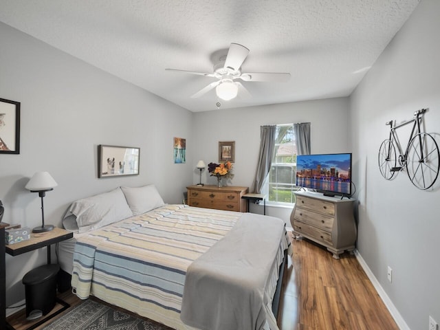 bedroom with ceiling fan, a textured ceiling, and hardwood / wood-style flooring