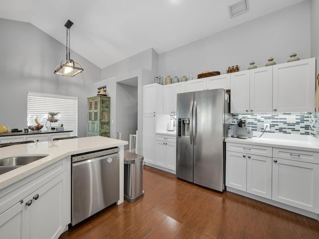 kitchen featuring lofted ceiling, backsplash, hanging light fixtures, appliances with stainless steel finishes, and white cabinets