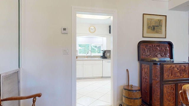 hall with visible vents, a sink, and light tile patterned floors