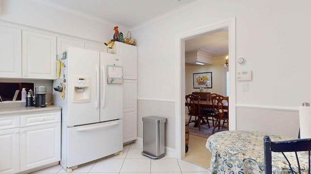 kitchen with ornamental molding, white refrigerator with ice dispenser, and white cabinets