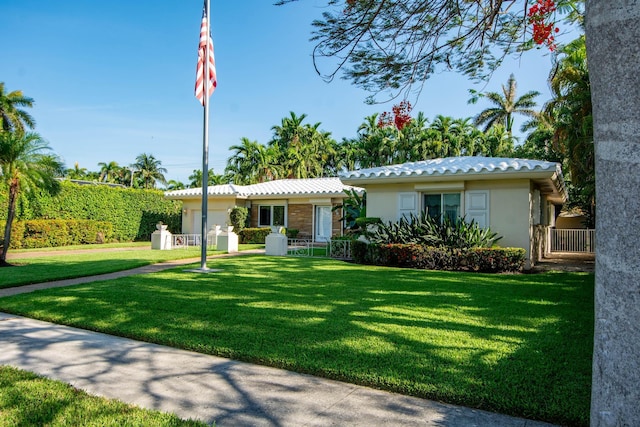 ranch-style house with a front yard, fence, a tiled roof, and stucco siding