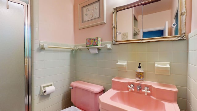 bathroom featuring a sink, tile walls, and toilet