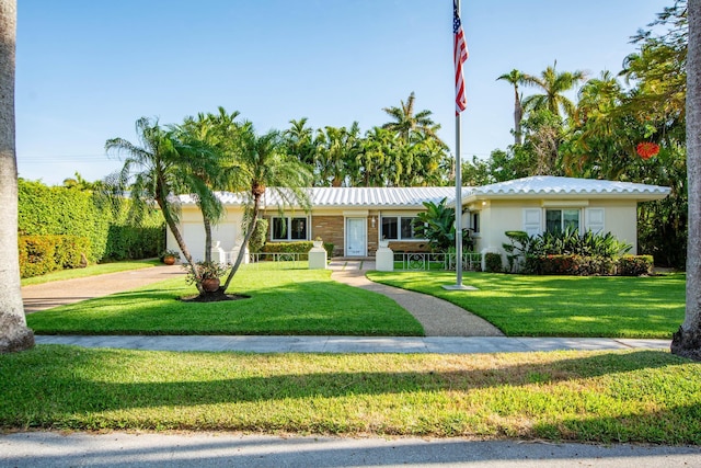 ranch-style home featuring driveway, an attached garage, a front lawn, and stucco siding