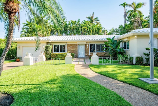 ranch-style house featuring a front yard, an attached garage, fence, and stucco siding