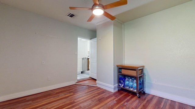 empty room featuring a ceiling fan, baseboards, visible vents, and wood finished floors