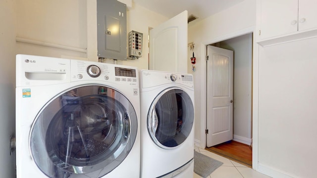 laundry area featuring light tile patterned floors, cabinet space, electric panel, independent washer and dryer, and baseboards