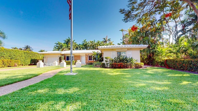 ranch-style home with a garage, a front lawn, fence, and stucco siding