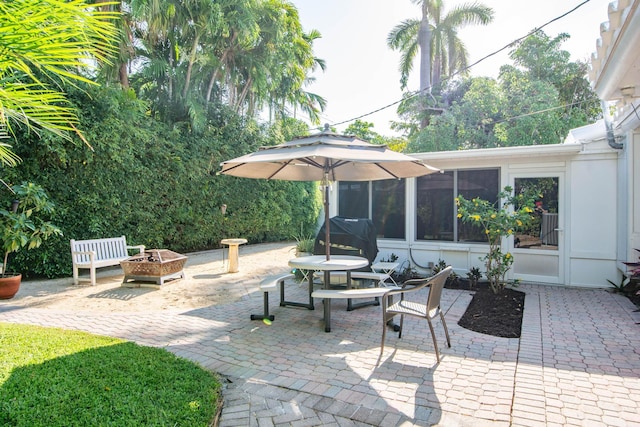 view of patio / terrace with an outdoor fire pit, a sunroom, and area for grilling