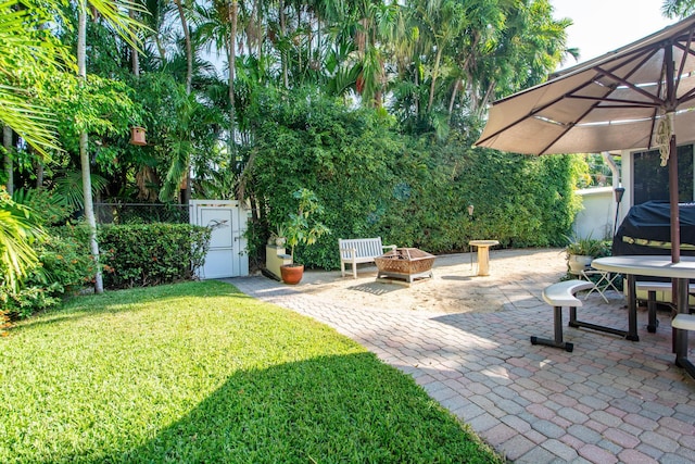 view of yard featuring a gate, a patio area, fence, and a fire pit