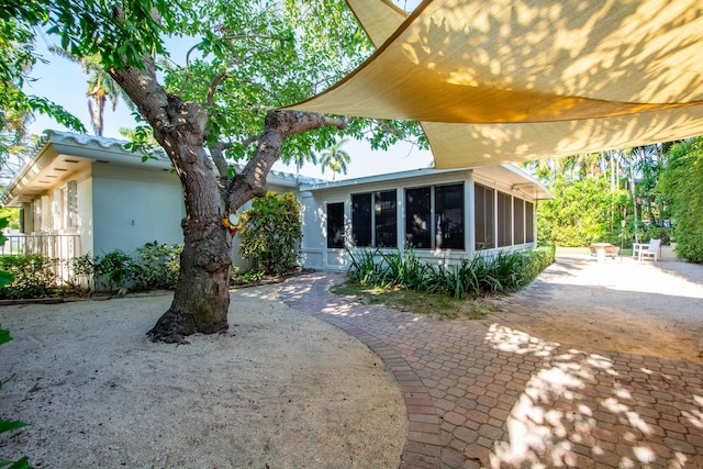 back of house with a sunroom and stucco siding