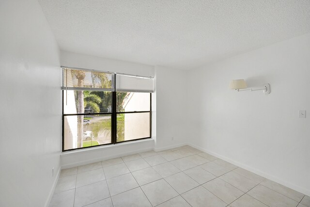 empty room featuring a textured ceiling and light tile patterned floors