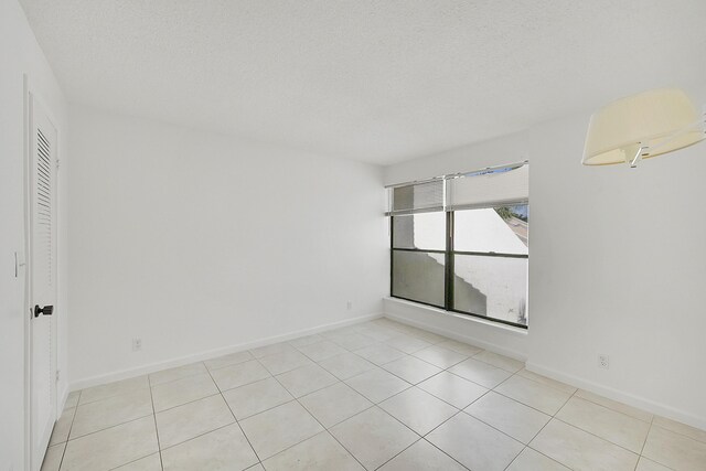 tiled empty room featuring a textured ceiling