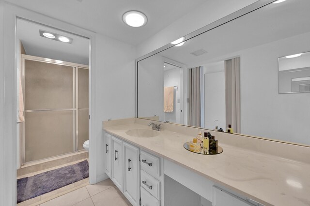 bathroom featuring toilet, vanity, tile patterned flooring, and walk in shower