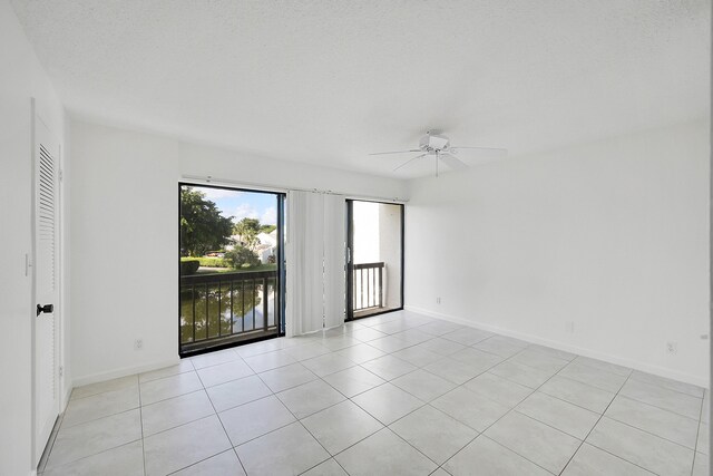 tiled empty room with ceiling fan and a textured ceiling